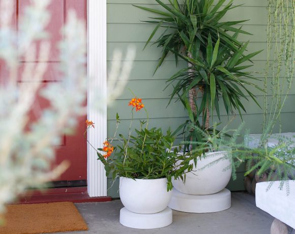 Two white planters by the front door of a home